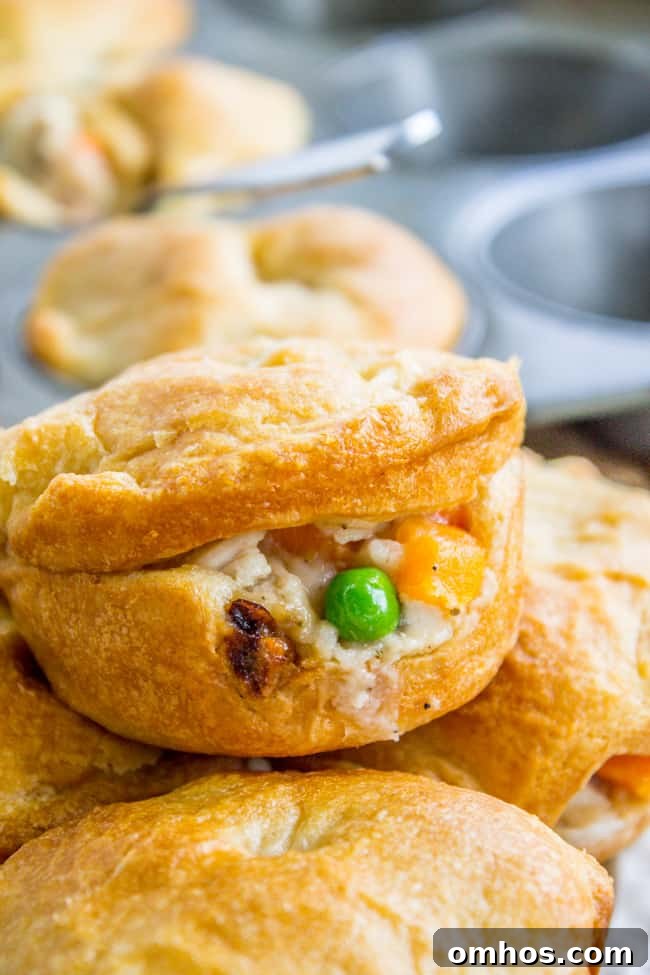 Individual mini chicken pot pies with crescent rolls stacked by a muffin tin.