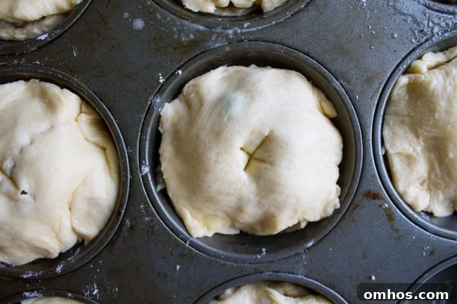 Uncooked mini chicken pot pies in a muffin tin with slits for venting steam.
