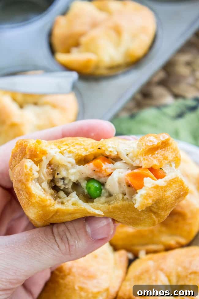Hand holding mini chicken pot pie with bite taken out and filling showing.
