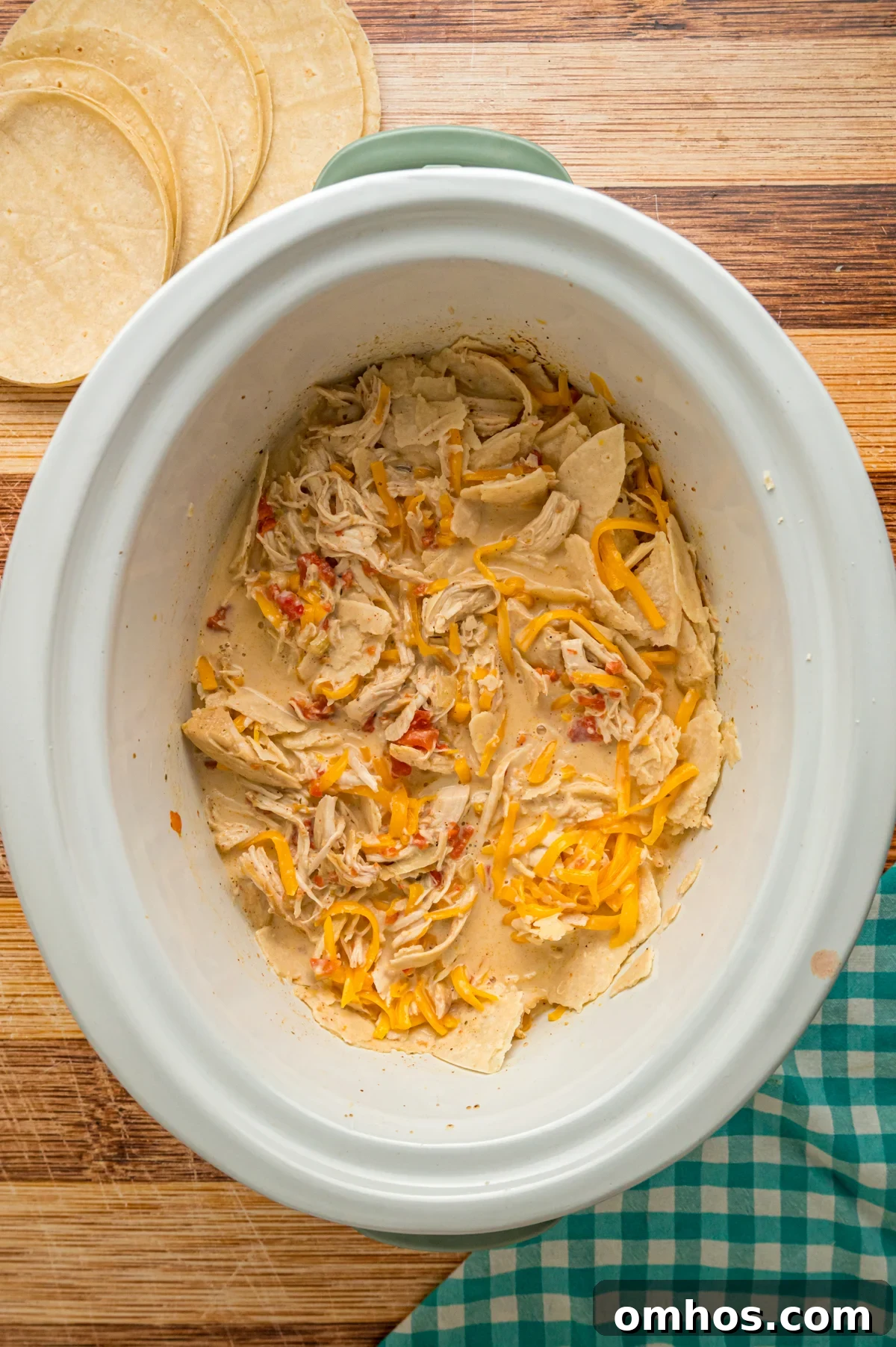 Classic King Ranch Chicken Casserole Recipe 5 Cream mixture, tortillas, and cheese added to cooked chicken in a crockpot.