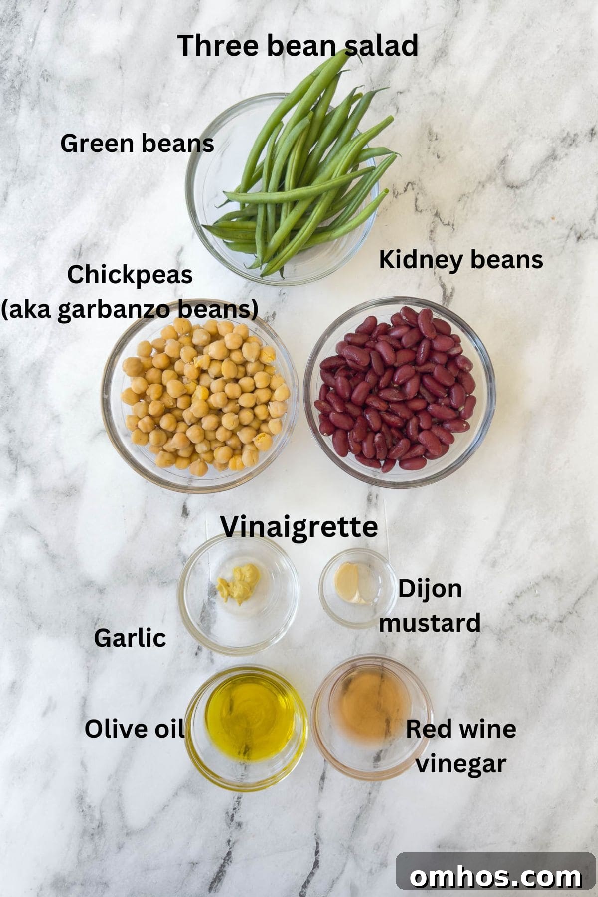 Ingredients for a three beans salad and vinaigrette on a marble counter.