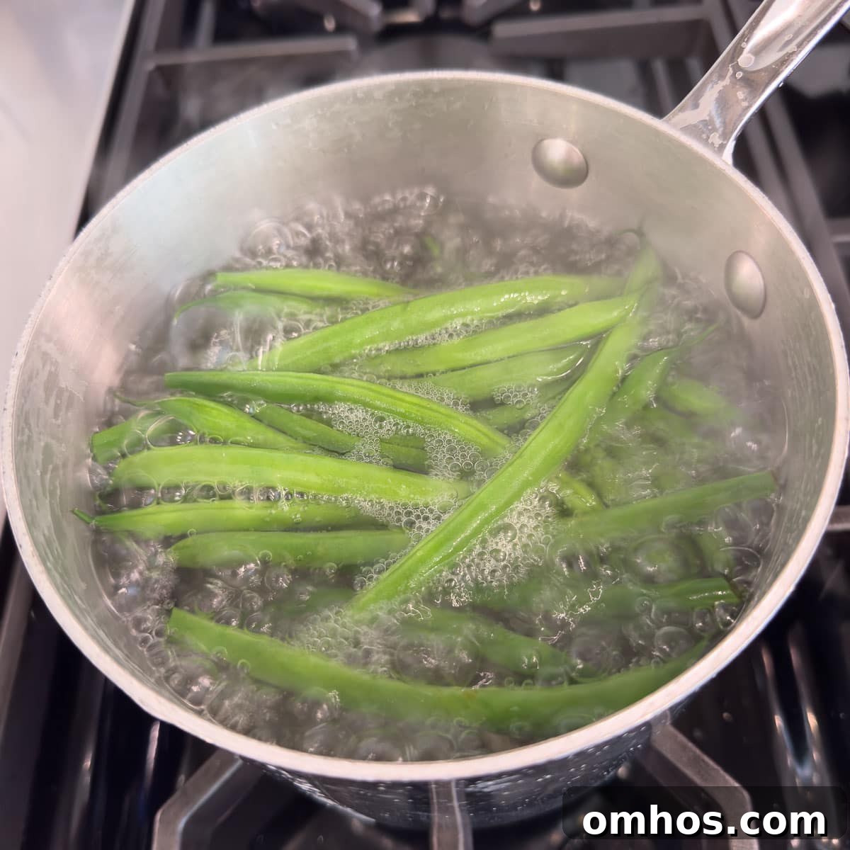 A small pot of boiling green beans on the stovetop.