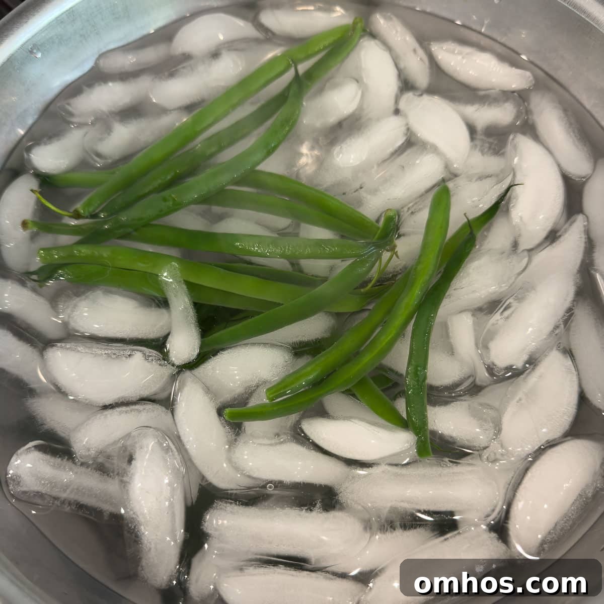 Cooked green beans in an ice bath chilling.