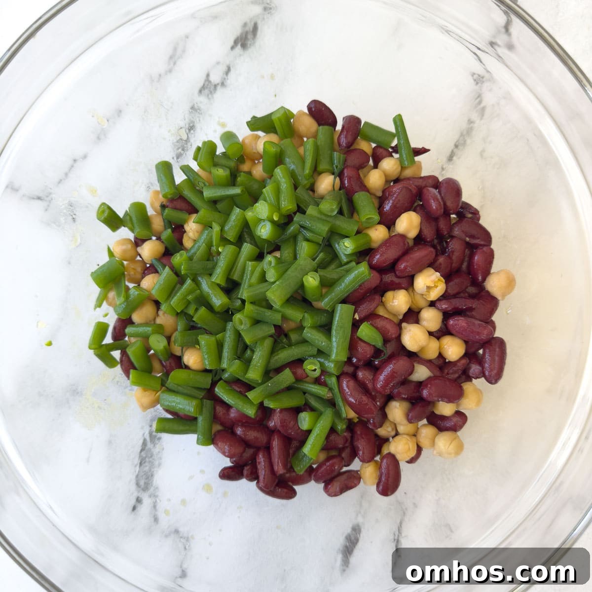 Kidney beans, green beans, and chickpeas mixed in a glass bow.