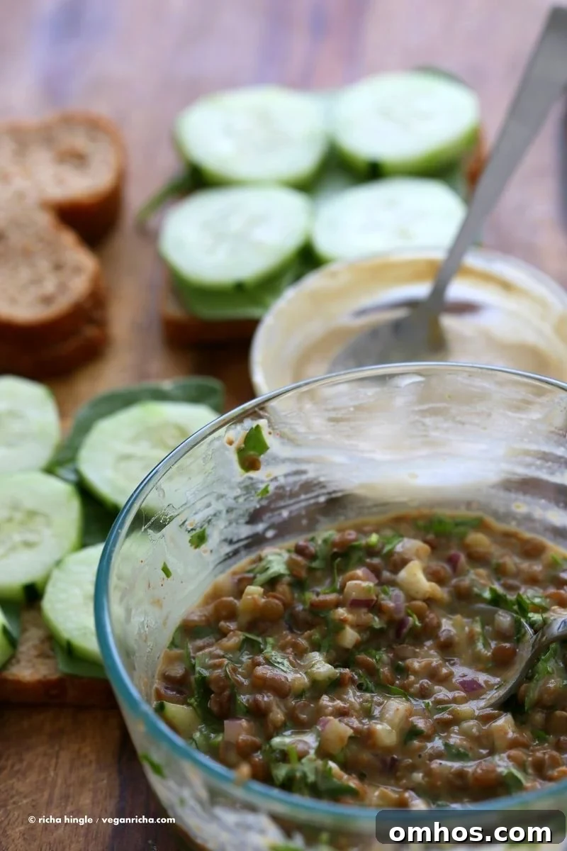 Layered falafel-spiced lentil salad sandwich with greens and cucumber.