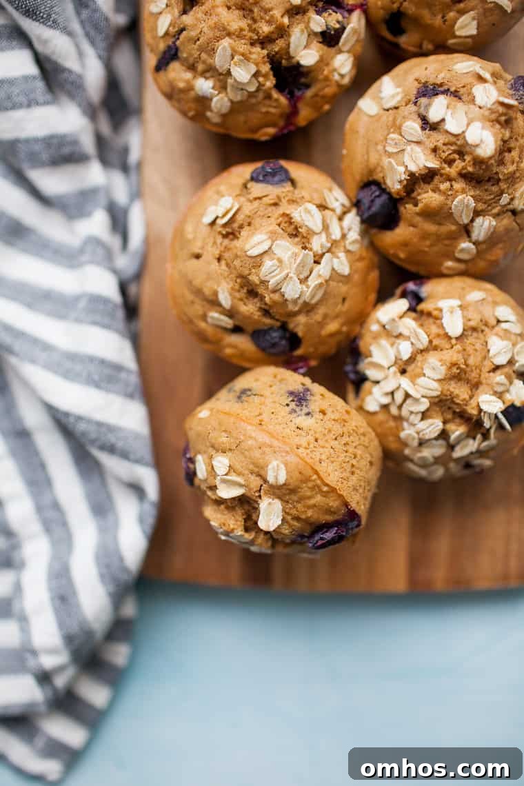 Moist Blueberry Oatmeal Muffins Recipe 9 blueberry oatmeal muffins scattered across a wood board