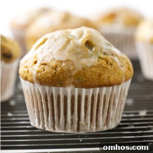 A zucchini muffin on a cooling rack with a sweet glaze.