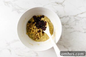 Adding toasted nuts and raisins to zucchini muffin batter recipe.