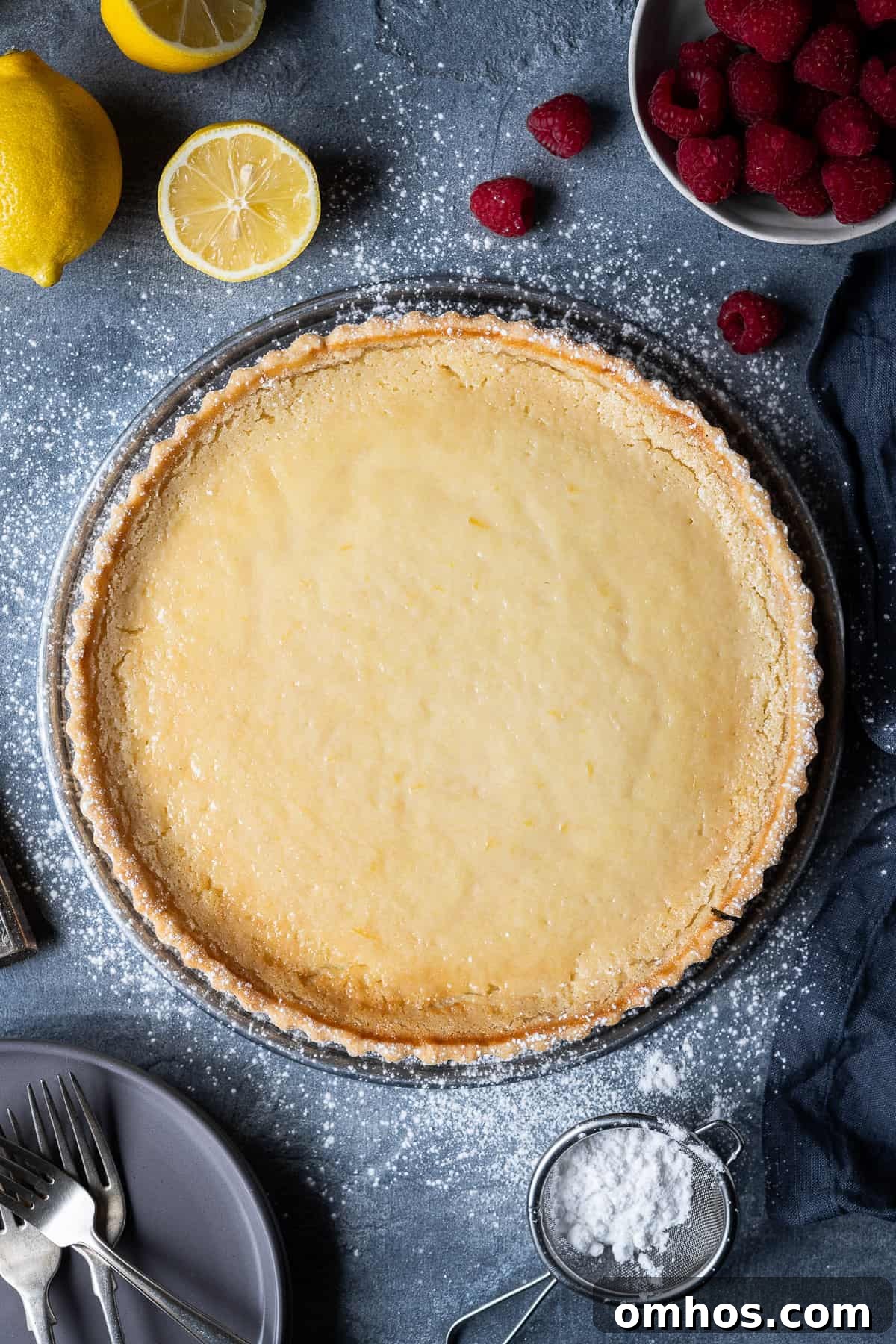 Vegan tarte au citron with raspberries Vegan tarte au citron on a grey background with lemons and raspberries