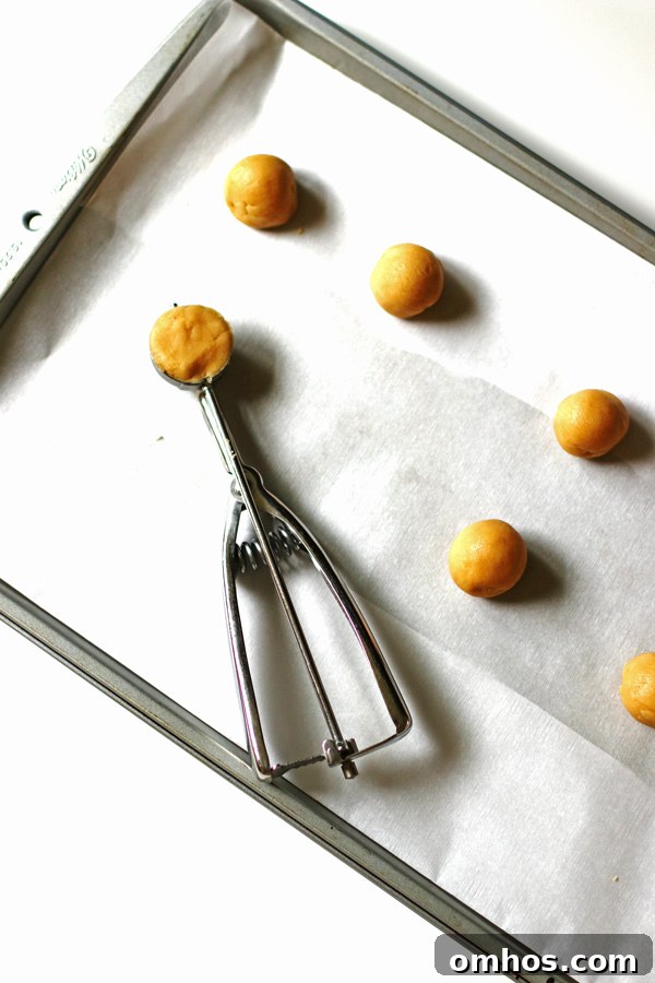Peanut butter dough balls on baking sheet covered with parchment paper
