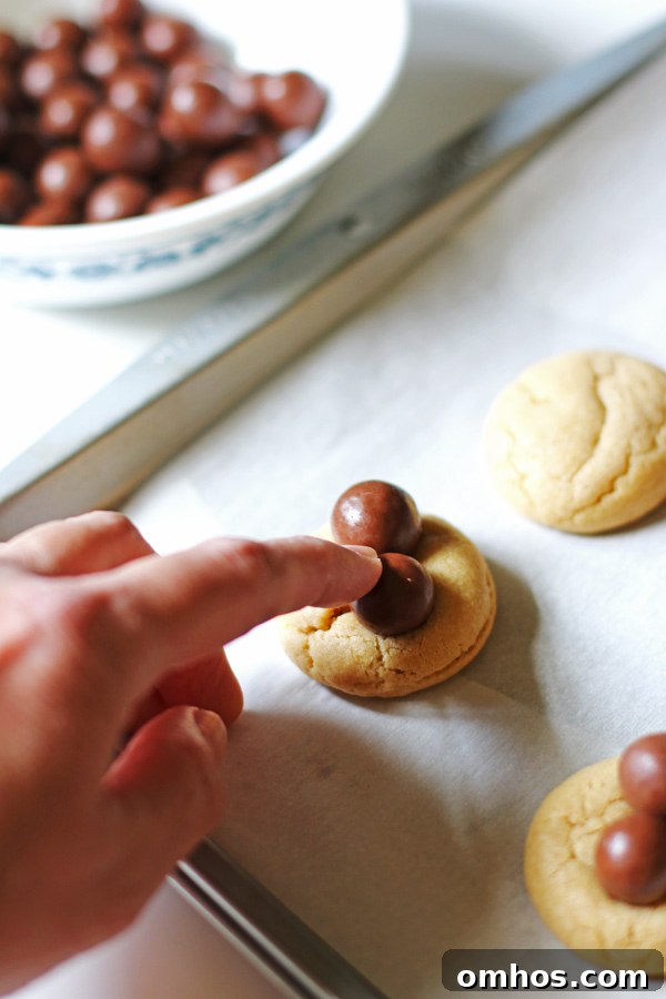 Pressing the whopper candy on top of the cookies to make the spiders