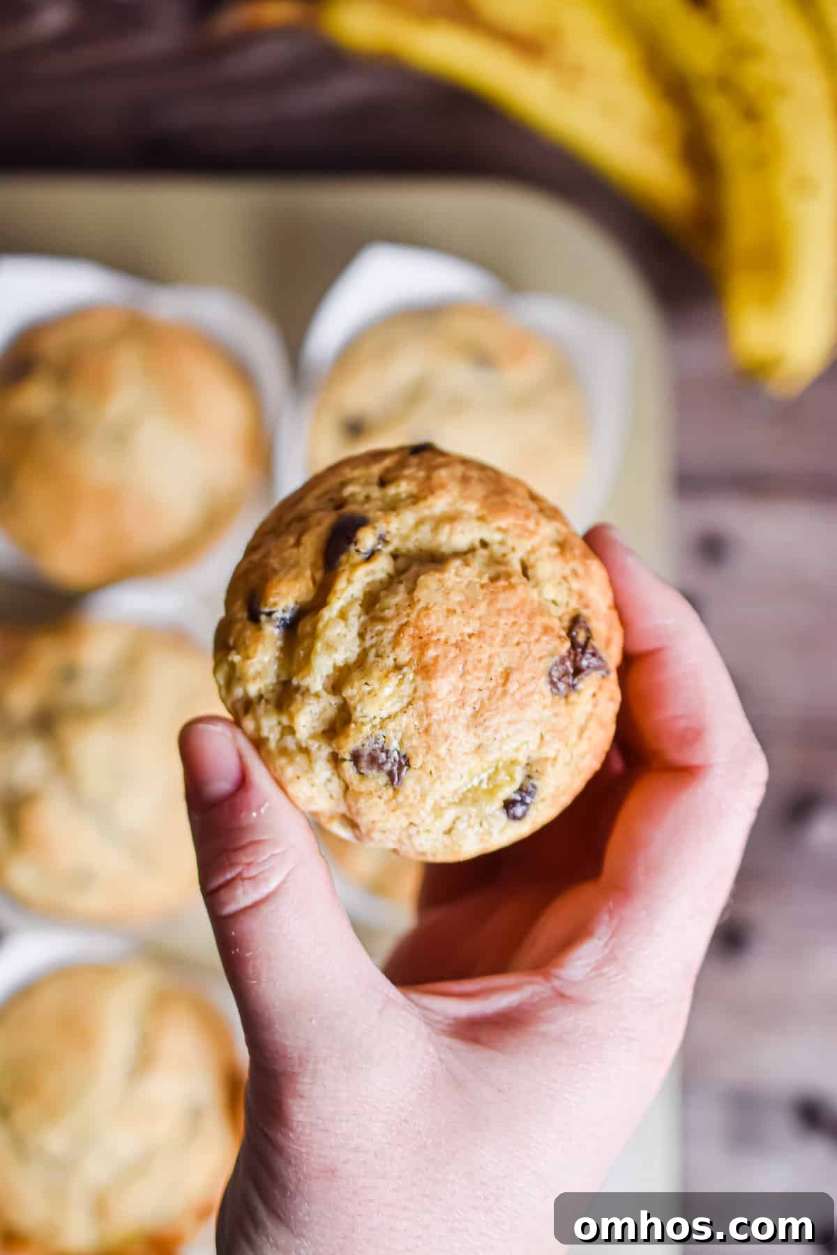 A hand is holding one banana muffins with self-rising flour