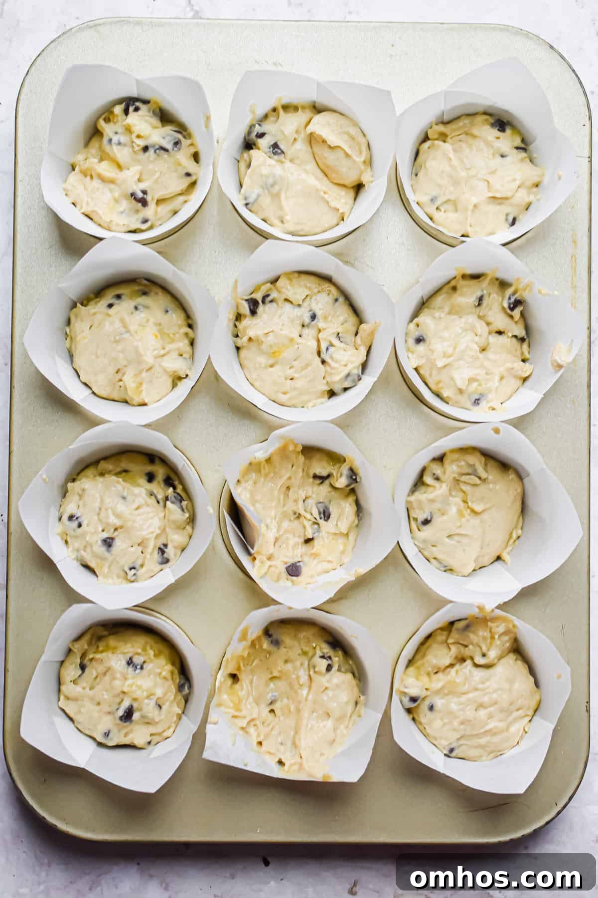The muffin liners are filled with the banana muffin batter.