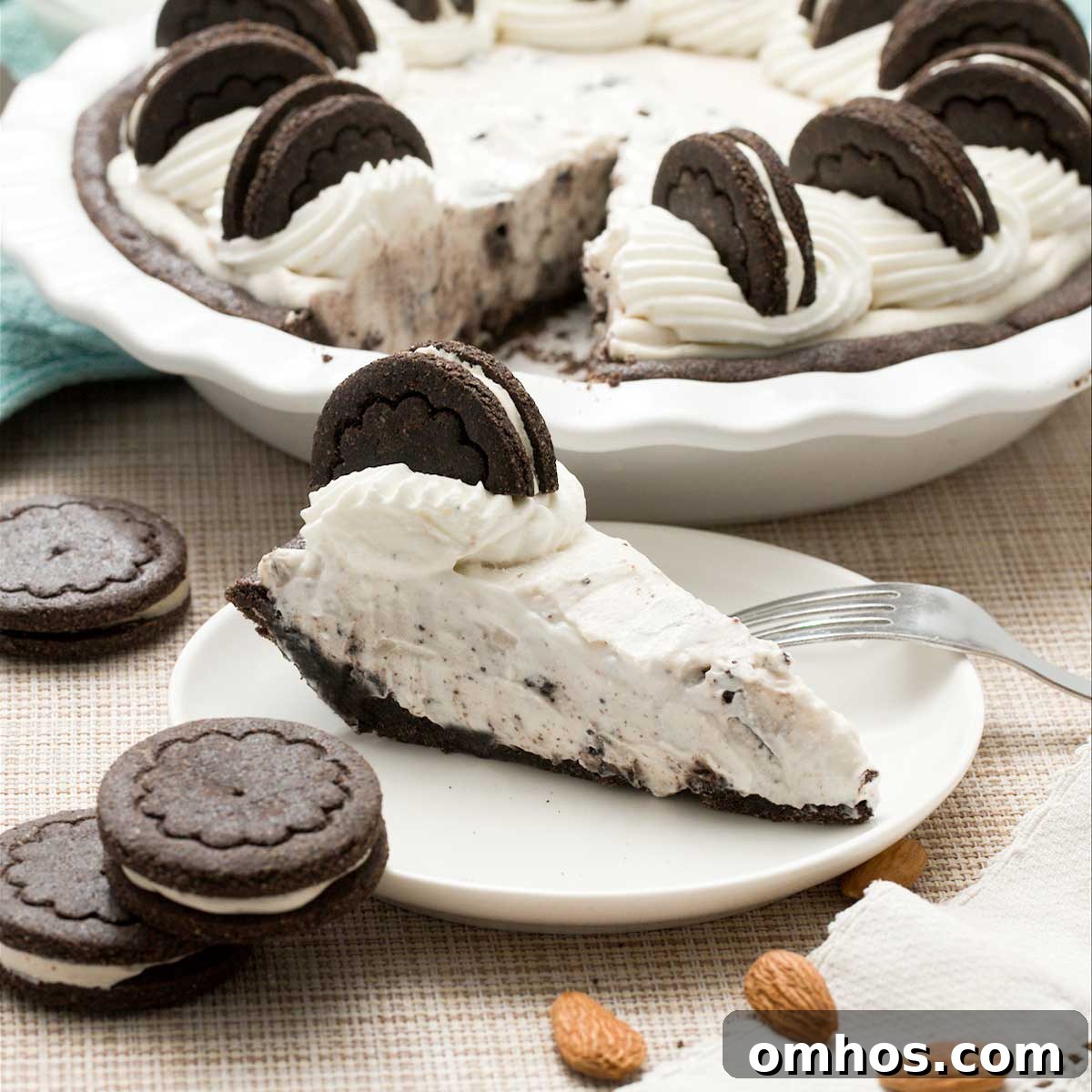 A gluten-free oreo cream pie with whipped cream on top and a slice on a plate.