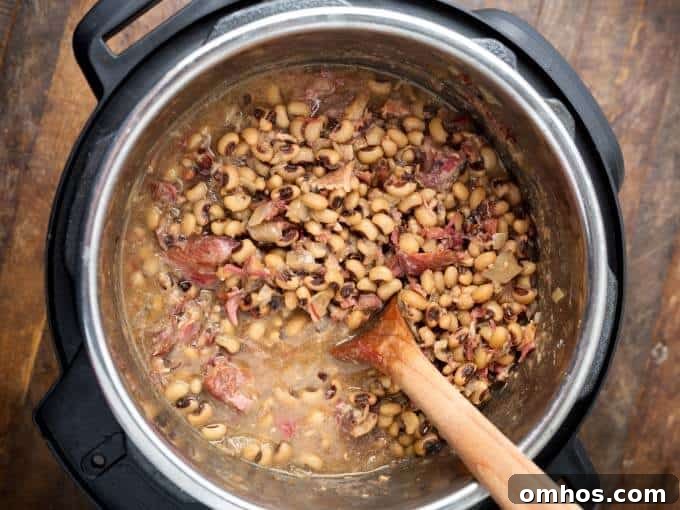 Southern Black Eyed Peas in pressure cooker with wooden mixing spoon