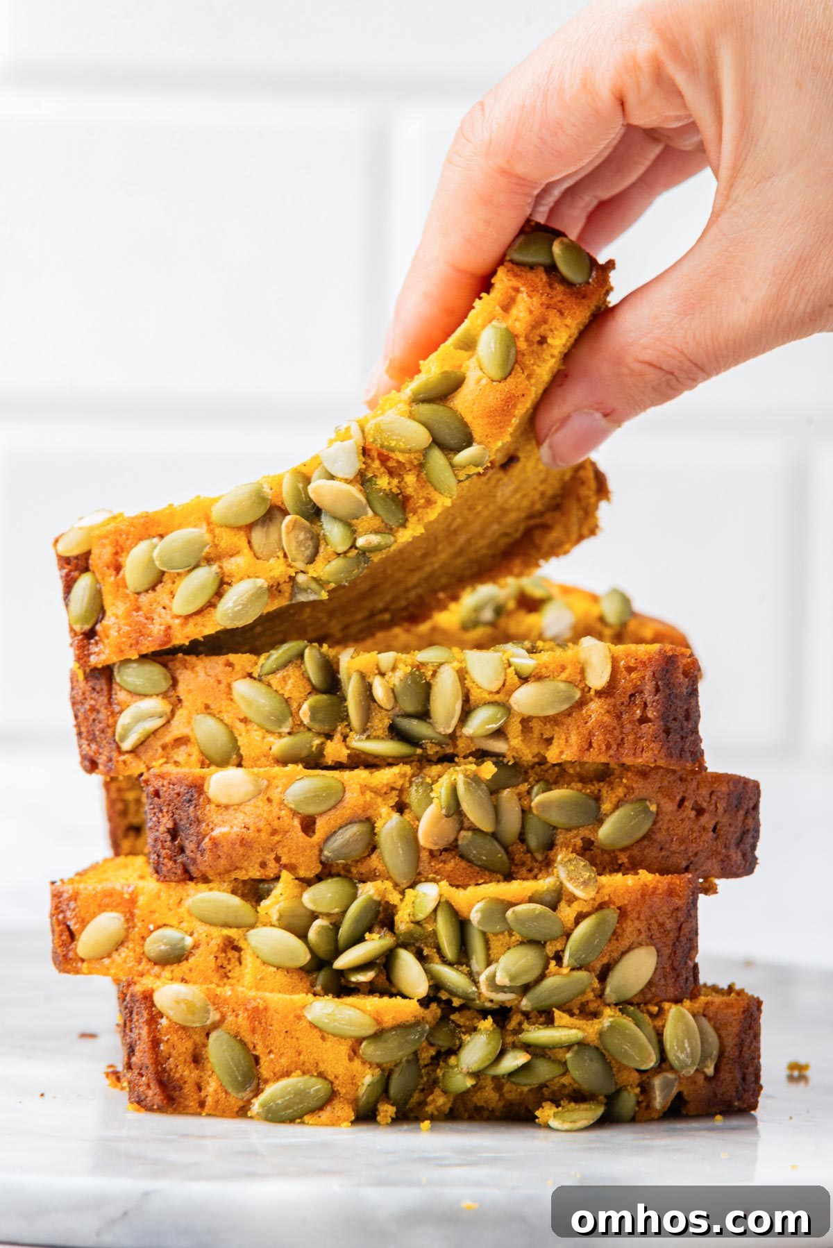 Starbucks-Style Pumpkin Bread Recipe 2 A top-down view of sliced pumpkin bread arranged neatly on a marble surface, highlighting the vibrant color and seed topping.