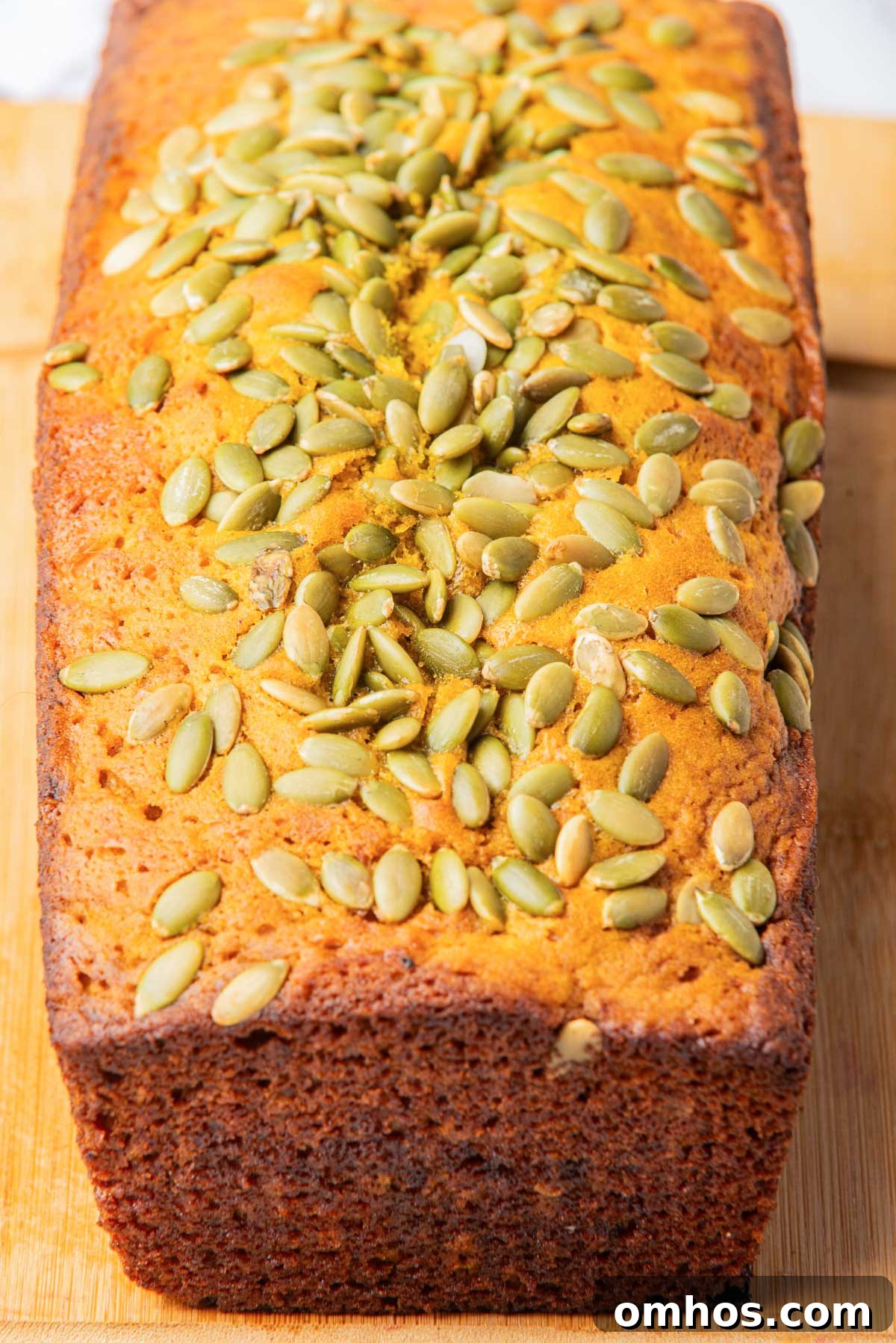 Starbucks-Style Pumpkin Bread Recipe 11 A top-down view of a loaf of pumpkin bread, showcasing the pumpkin seeds topping and golden-brown crust.