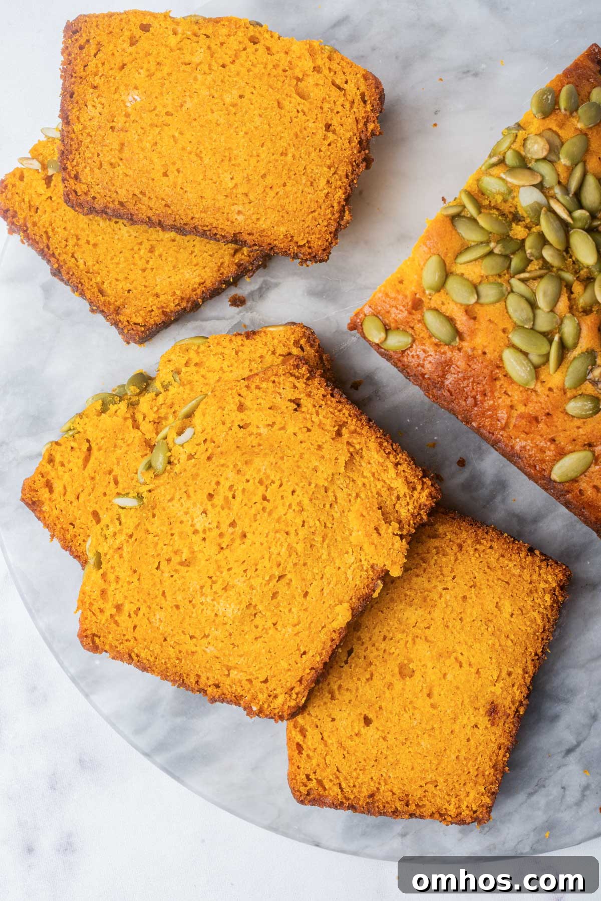 Starbucks-Style Pumpkin Bread Recipe 3 A top-down view of sliced pumpkin bread arranged neatly on a marble surface, highlighting the vibrant color and seed topping.