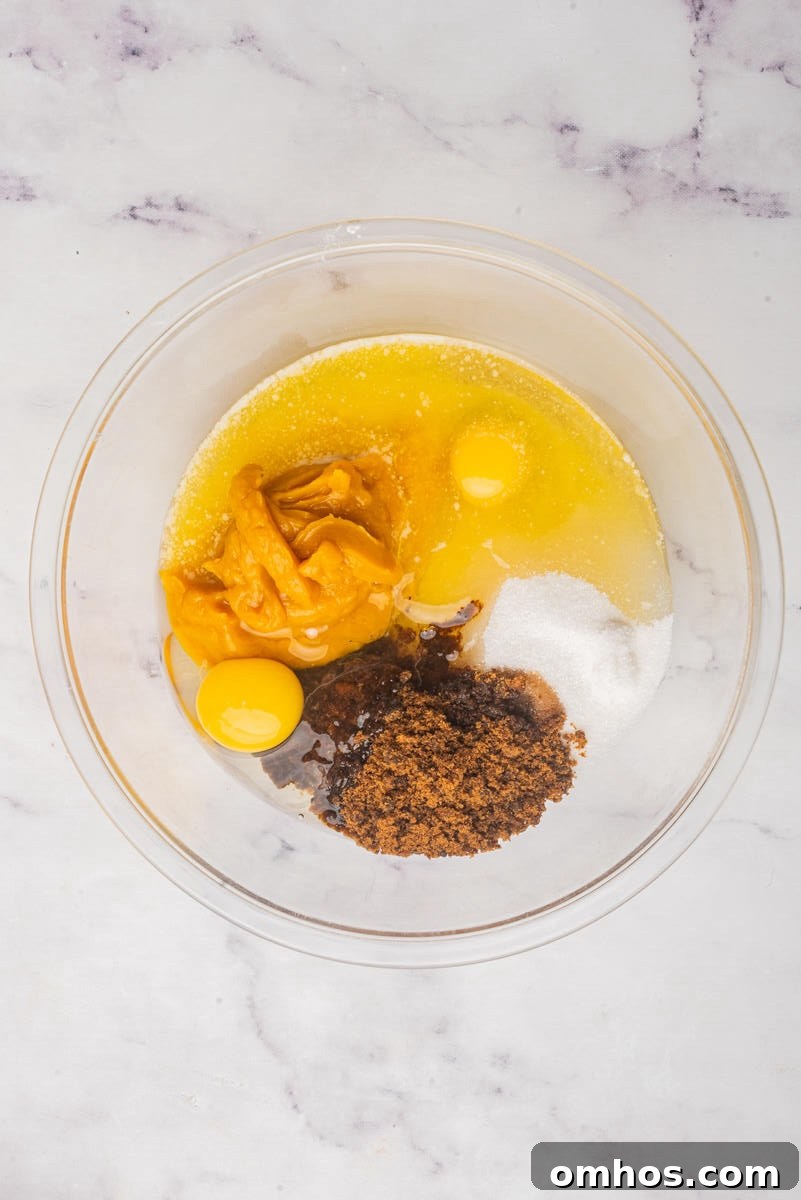 Starbucks-Style Pumpkin Bread Recipe 6 A glass bowl with wet ingredients for baking, including eggs, pumpkin puree, melted butter, brown sugar, and granulated sugar.