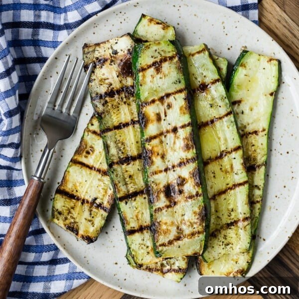 Grilled zucchini slices on a speckled plate beside a fork.