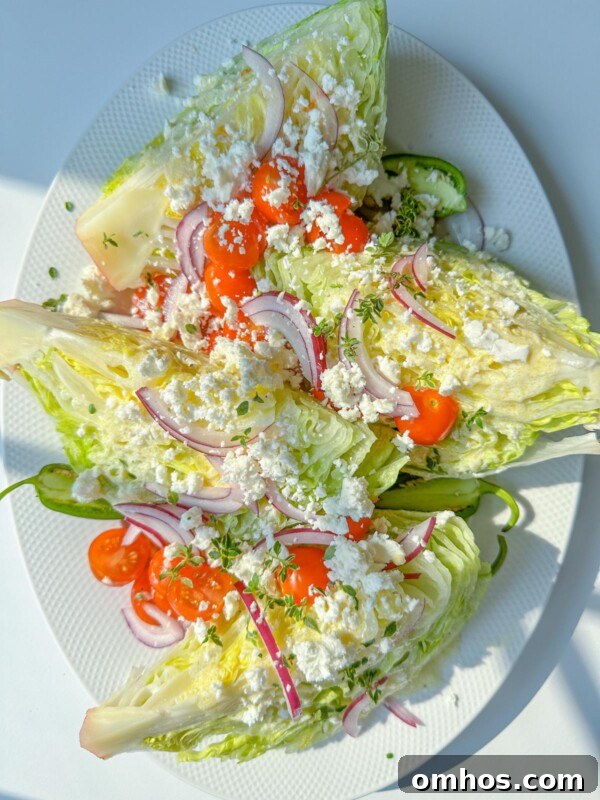 Classic Iceberg Wedge Salad with Blue Cheese and Bacon 3 Three wedge salads on a plate with tomatoes and feta
