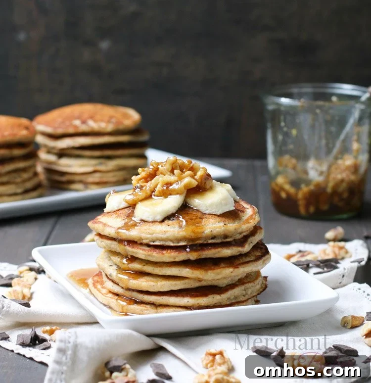 Stack of Oatmeal Chocolate Chip Banana Pancakes topped with sliced bananas and walnut syrup