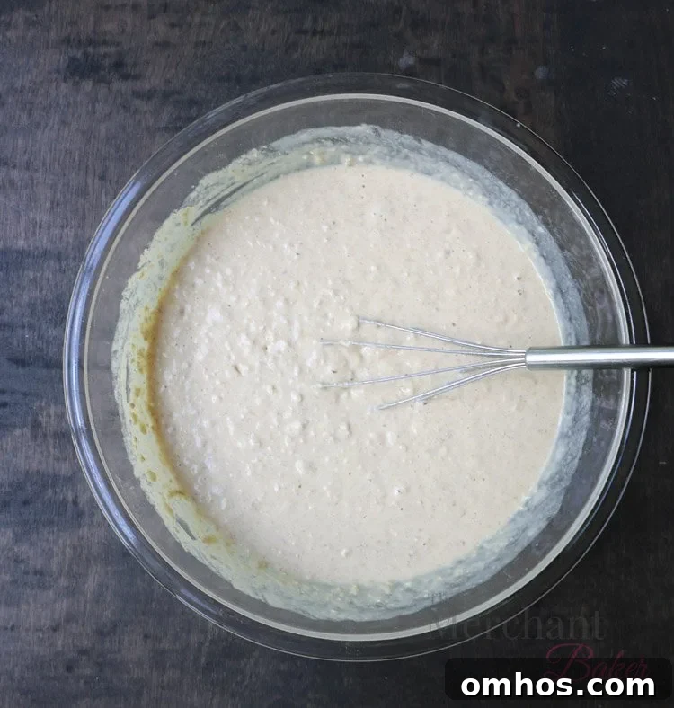 Bowl of Oatmeal Chocolate Chip Banana Pancake batter in a glass bowl with a whisk