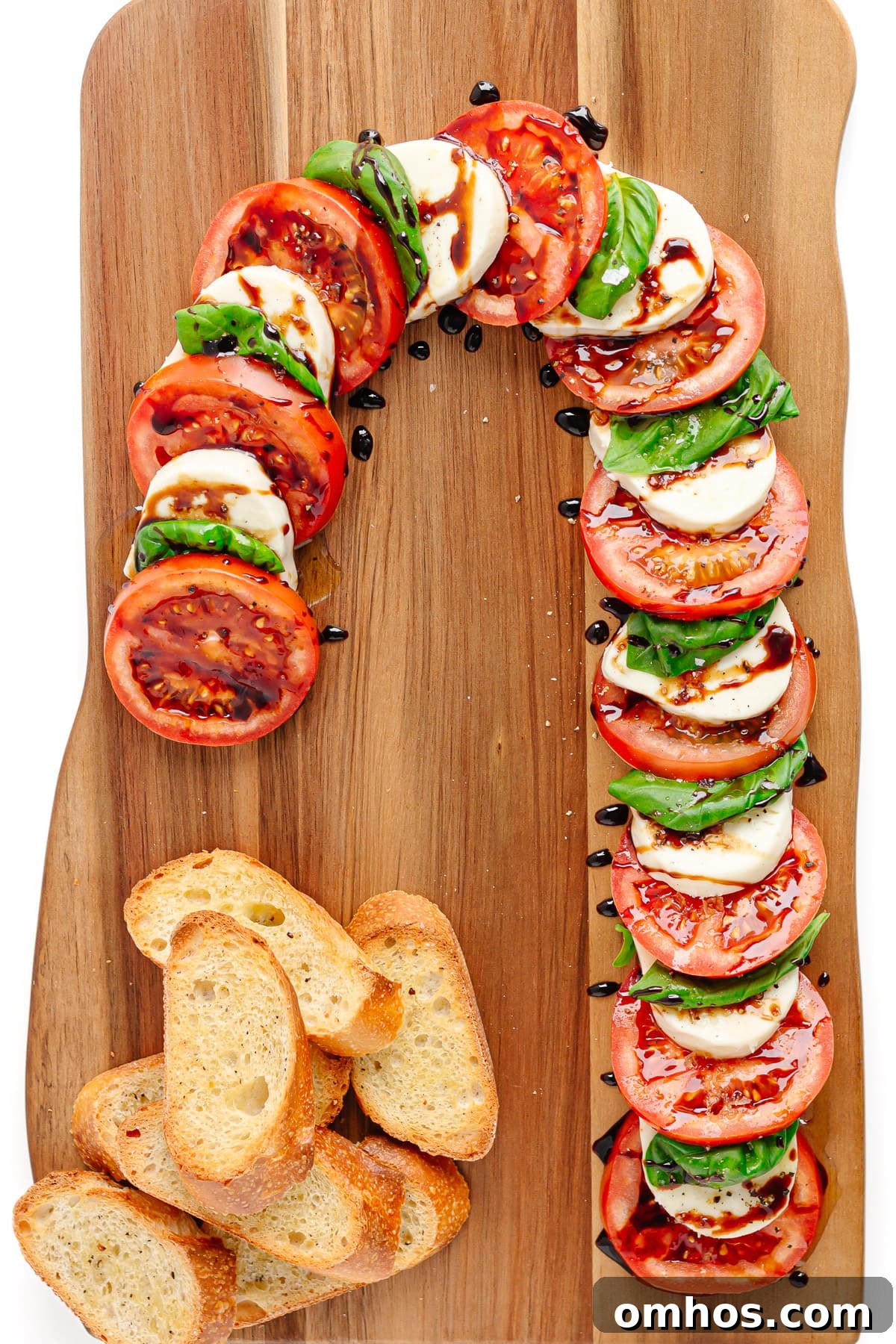Candy cane caprese with crostini on a wooden board.