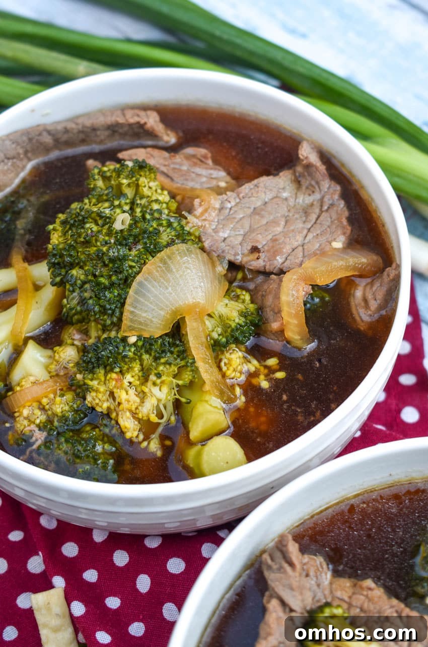 chinese beef and broccoli soup in two white bowls with green onions on the side