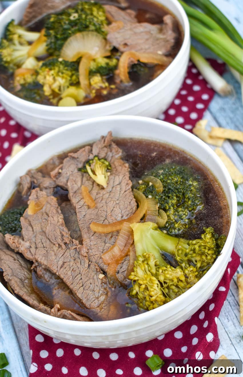 chinese beef and broccoli soup in two white bowls with green onions on the side