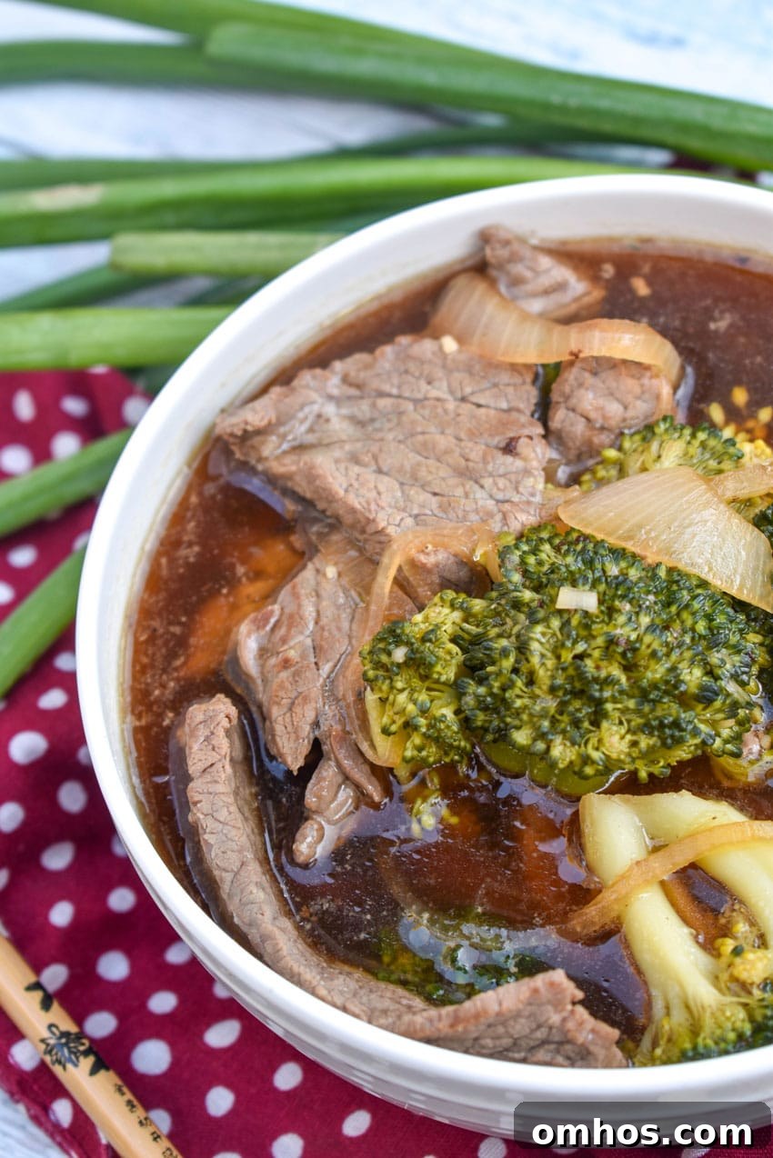 chinese beef and broccoli soup in two white bowls with green onions on the side