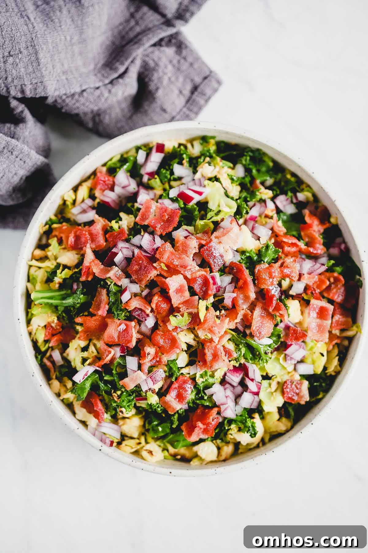 Overhead photo of a white bowl with a Brussels sprouts bacon salad.