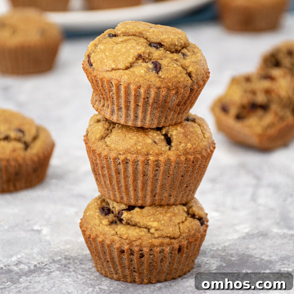 A stack of 3 blender flourless banana muffins with mini chocolate chips making a muffin tower.