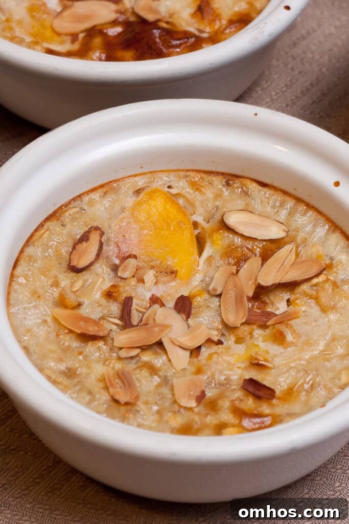a small ramekin filled with peaches and oatmeal topped with slivered almonds.