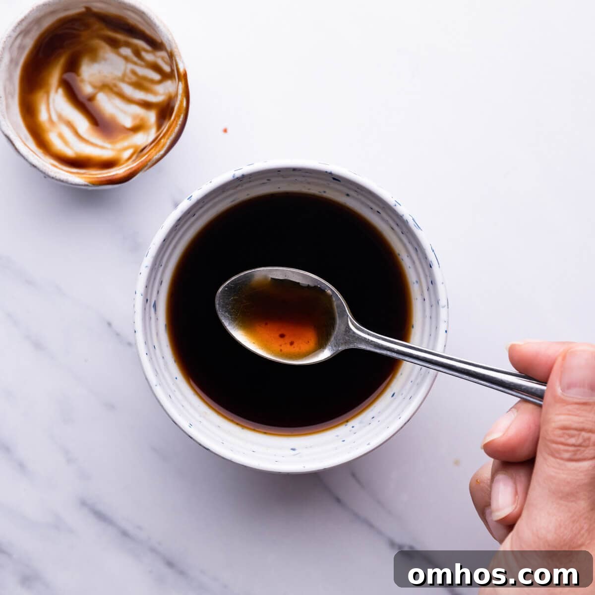 top view of a person mixing the sauce with teaspoon