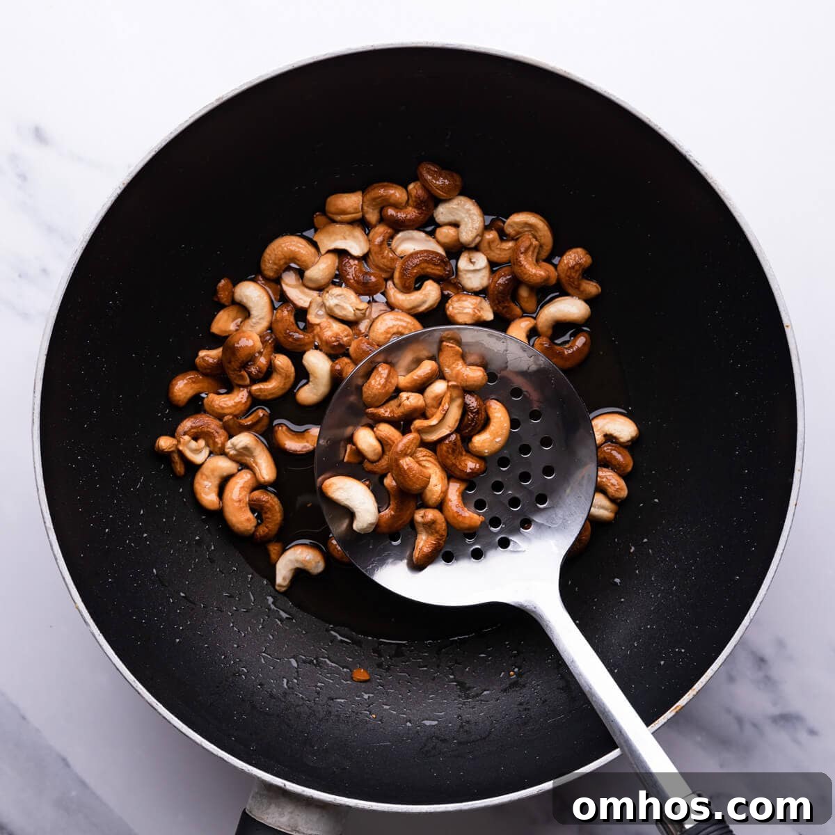 top down view of a wok with fried cashew nuts