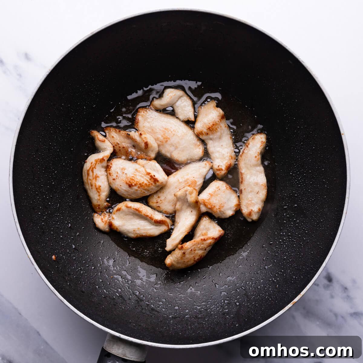 top down view of chicken being fried in the wok pan