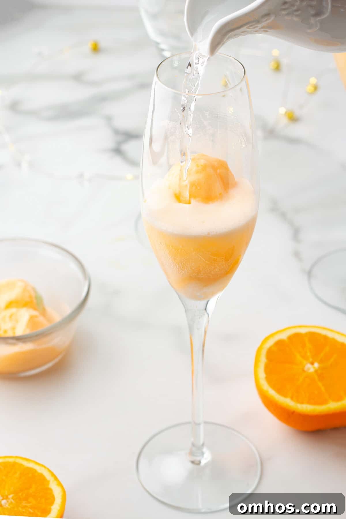 pouring sparkling water into a champagne flute with a scoop of orange sherbet