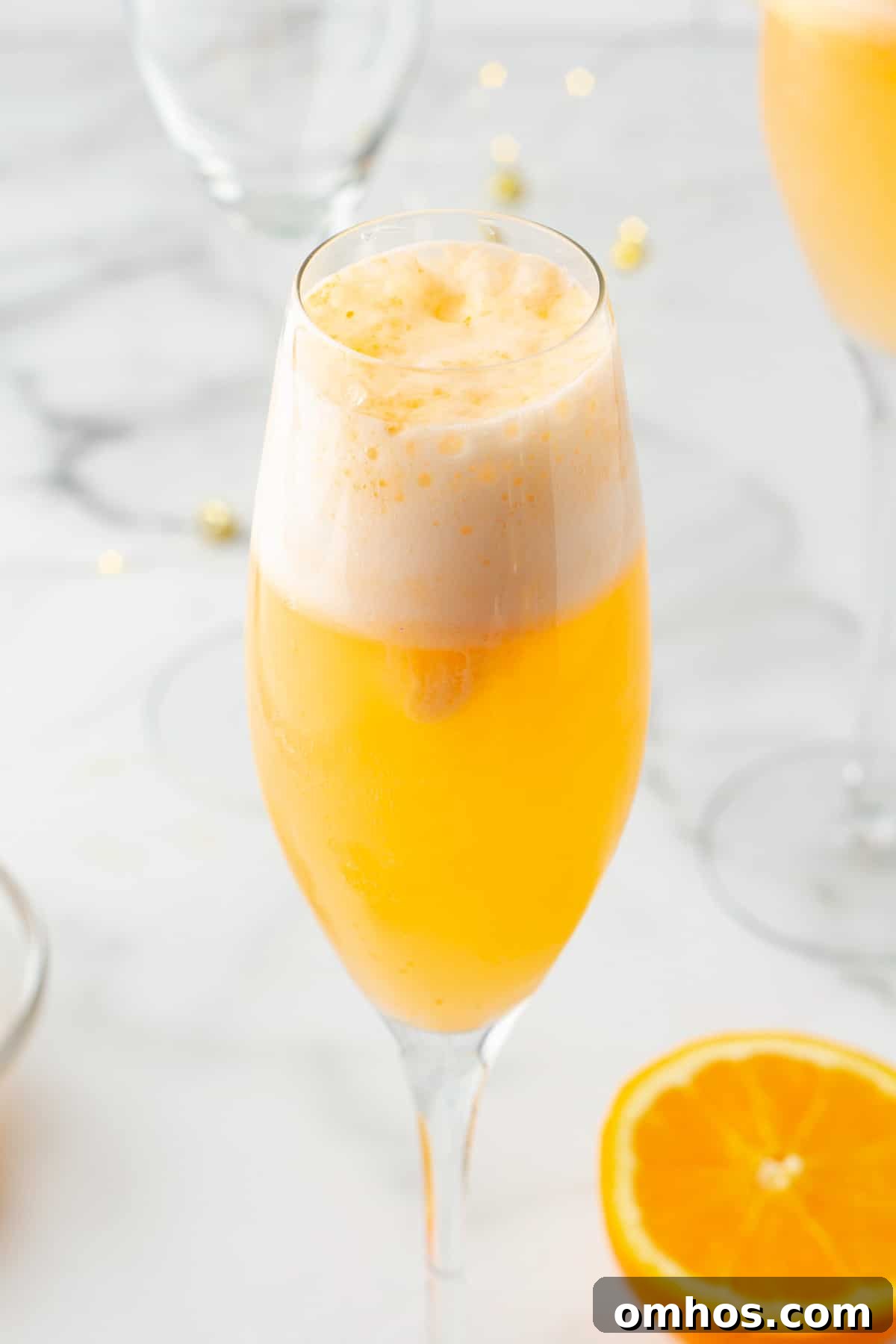 side view of an orange sherbet mimosa mocktail in a champagne flute