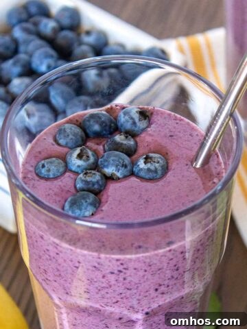 Blueberry banana spinach smoothie in a 16 ounce cup. There is a second smoothie off to the side.