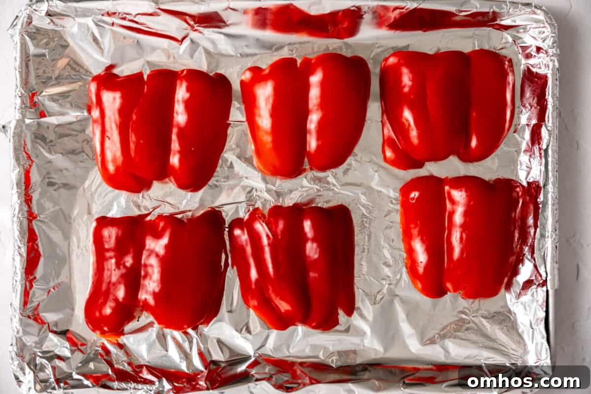 Red peppers sliced and on a baking sheet to roast.