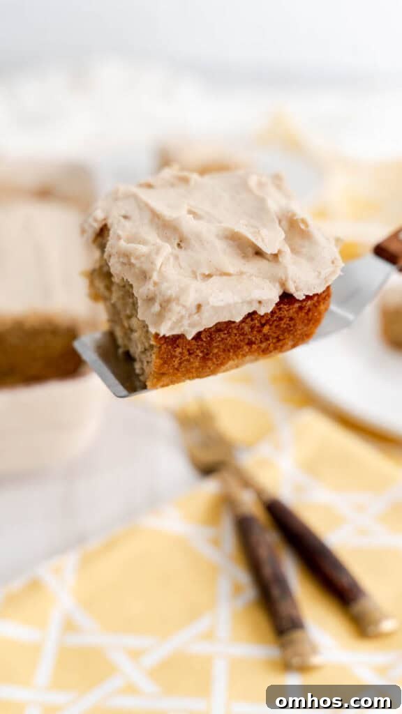 Moist Banana Cake Recipe with Cream Cheese Frosting 3 A slice of banana cake with cinnamon cream cheese frosting resting on a cake serve with a wooden handle.