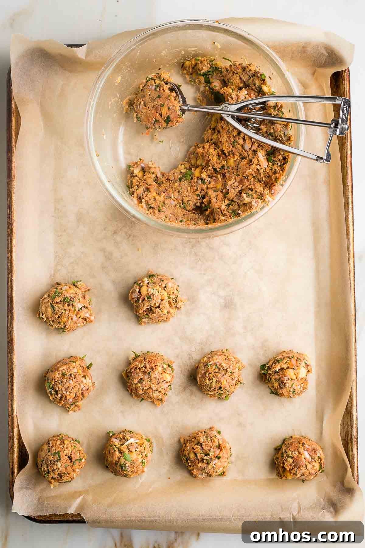 Vegan meatballs on a baking tray. Bowl with batter plus scooper too.