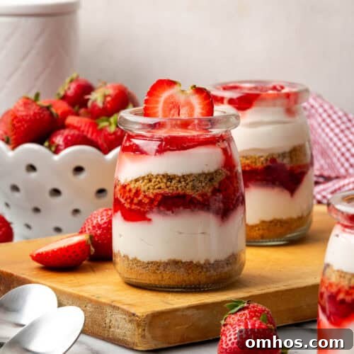A jar of strawberry no bake cheesecake sitting on a wood board.