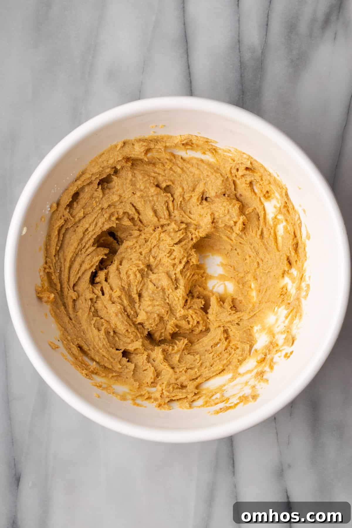Peanut butter creamed with cream cheese in a large white bowl.