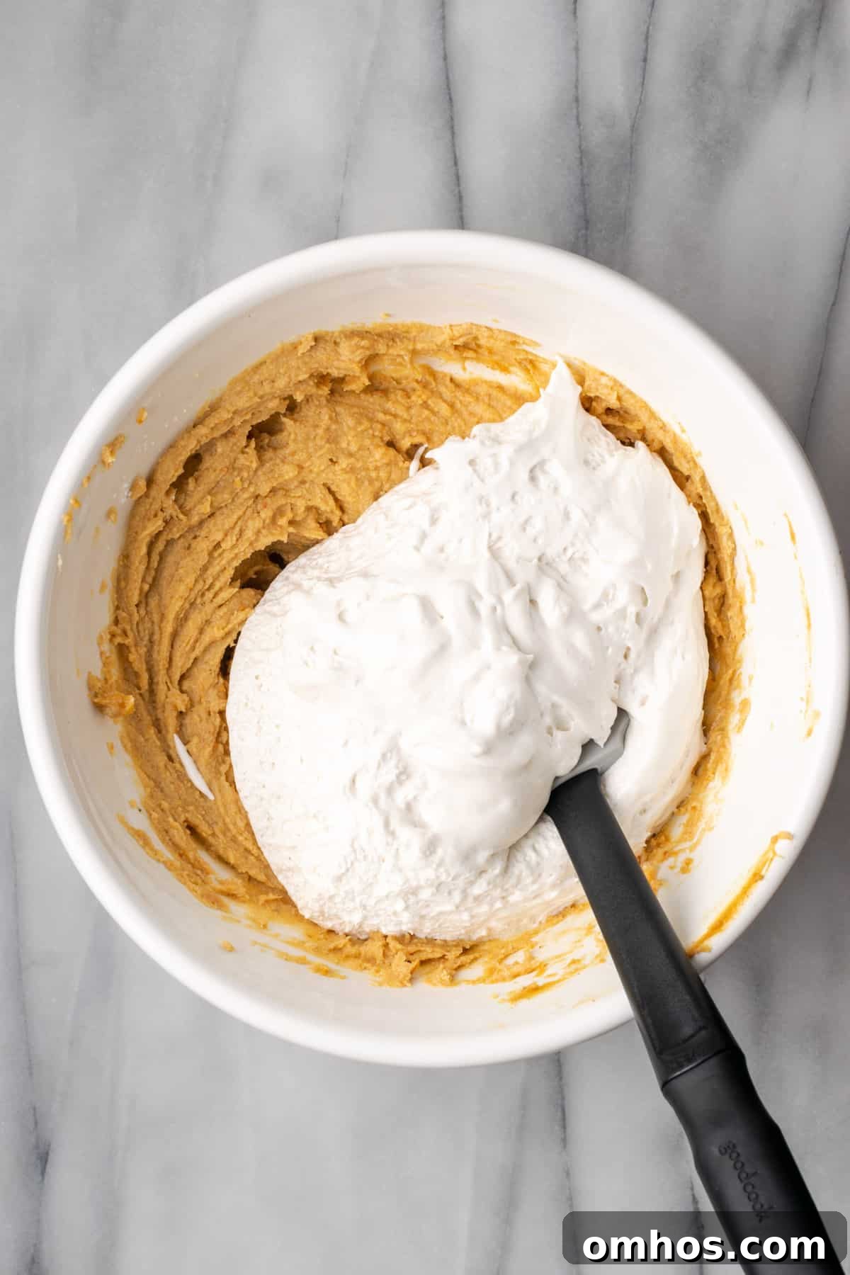 Whipped cream added to the peanut butter mixture in a large white bowl.