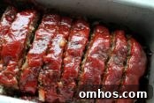 Slice meatloaf with a ketchup glaze on top in a loaf pan
