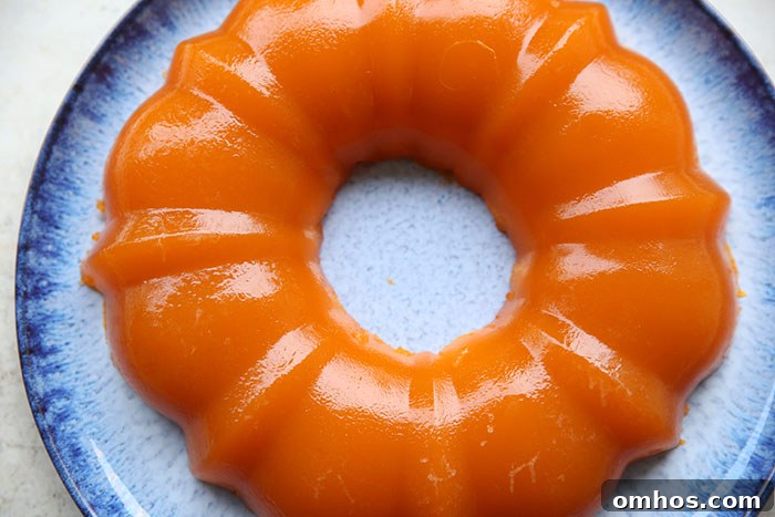 A bundt-shaped mandarin orange Jello salad on a large round blue plate.