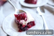 silver spoon next to a plate of a purpose jello dessert