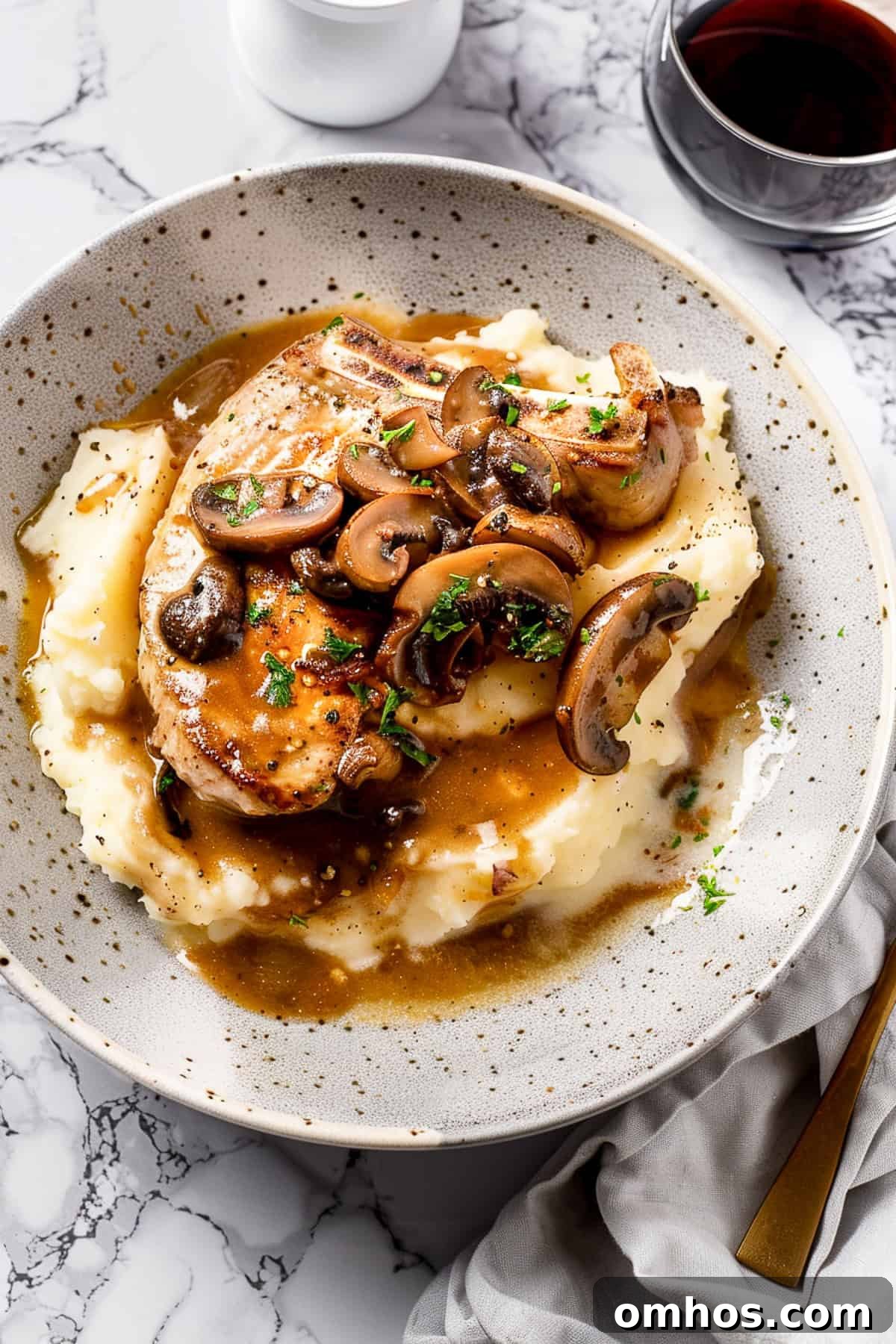 Crock pot pork chops over mashed potatoes with herbs and mushroom sauce.